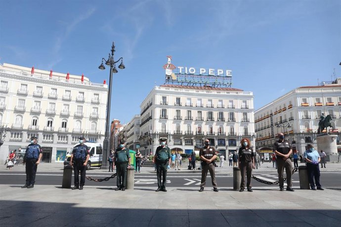 Miembros de distintos cuerpos de seguridad, como la Guardia Civil y la Policía Municipal de Madrid, guardan un minuto de silencio en memoria por los fallecidos por el COVID-19 en la Puerta de Sol.