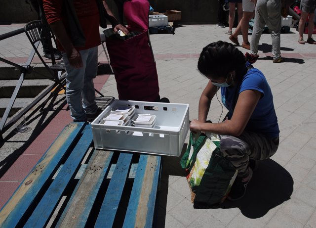 Una mujer recoge productos a las puertas de la Parroquia Santa María Micaela en Madrid