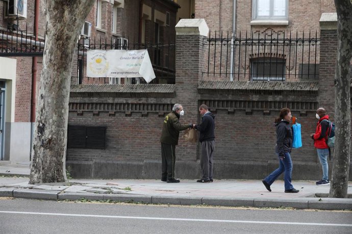 Varias personas esperan en cola para entrar en el comedor de las Hijas de la Caridad de San Vicente de Paúl en el madrileño barrio de Chamberí, a 28 de abril de 2020.