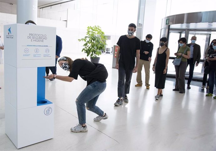 Visitantes del CaixaForum de Barcelona usan un dispensador de gel antes de acceder a las salas de exposición.