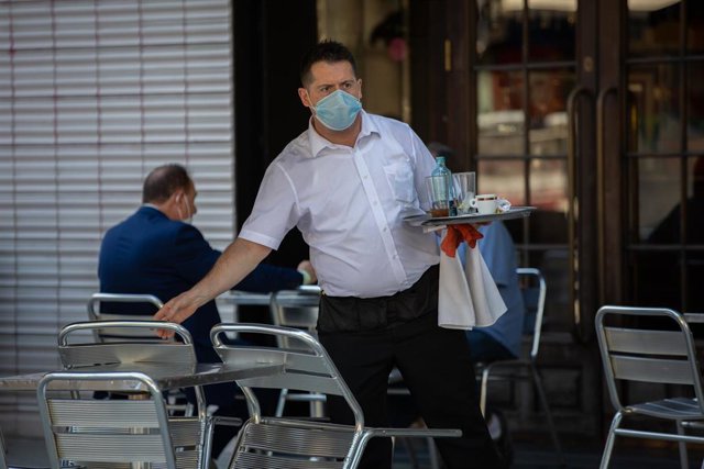 Un camarero sirve en la terraza de un bar durante el segundo día de la Fase 1 en Barcelona, Catalunya (España) a 26 de mayo de 2020.