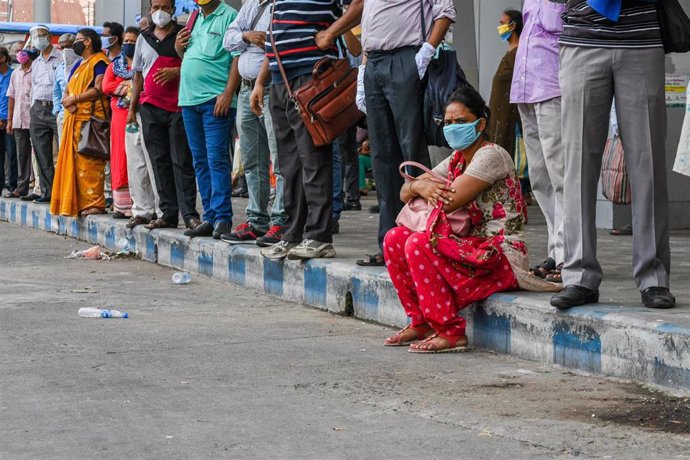 Personas con mascarillas esperan el autobús en Calcuta