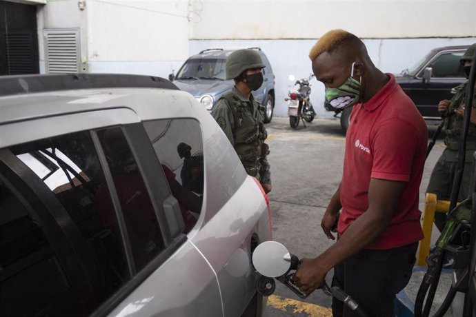 Un hombre con mascarilla echa gasolina de Caracas