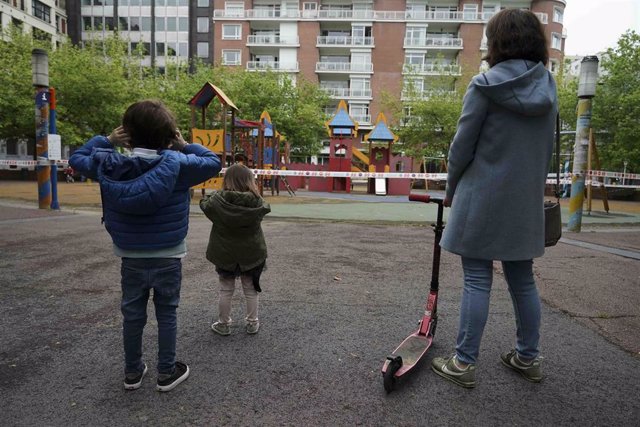 Un niño y una niña frente a un parque infantil clausurado, el primer día en el que los menores de 14 años pueden salir a la calle, en Bilbao
