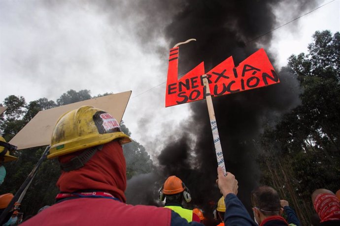 Participantes protegidos con mascarilla sujetan una pancarta durante la manifestación del comité de empresa de Alcoa 