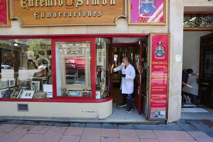 Un trabajador limpia la entrada de su tienda