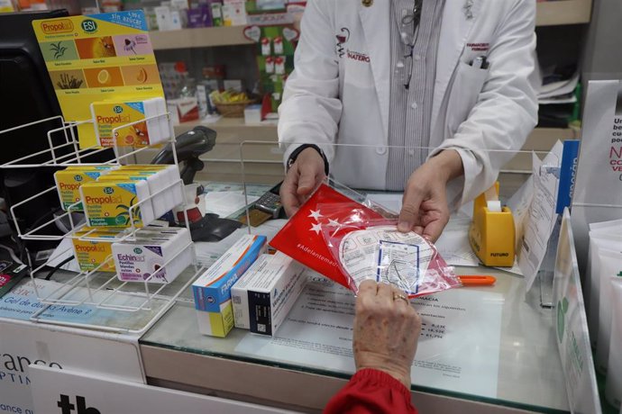 Un farmaceútico entrega a un cliente una de las siete millones de mascarillas FFP2 modelo KN95 