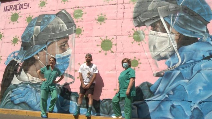 El artista urbano Alejandro Pajuelo junto a dos sanitarias en el graffiti que ha realizado en homenaje a los sanitarios