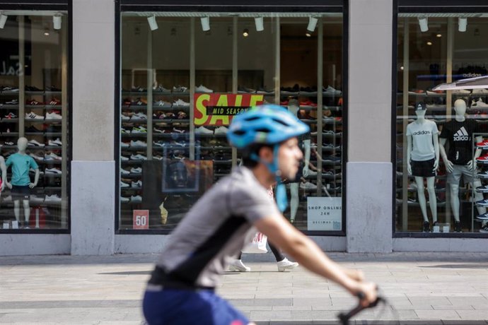 Un ciclista pasa junto a una tienda abierta durante la fase 1 de la desescalada en Madrid