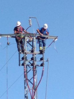 Dos operarios trabajan en el tendido eléctrico