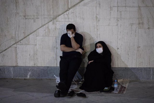 Una pareja sentada junto a una mezquita en Teherán