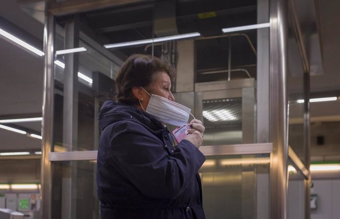 Una mujer se pone una mascarilla en una estación del metro de Sevilla