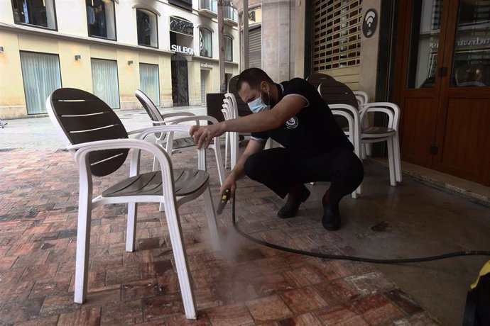 Trabajadores de la cafetería Central ubicada en la Plaza de La Constitución, en Málaga se afanan en la limpieza de los enseres de la terraza. Málaga a 20 de mayo del 2020