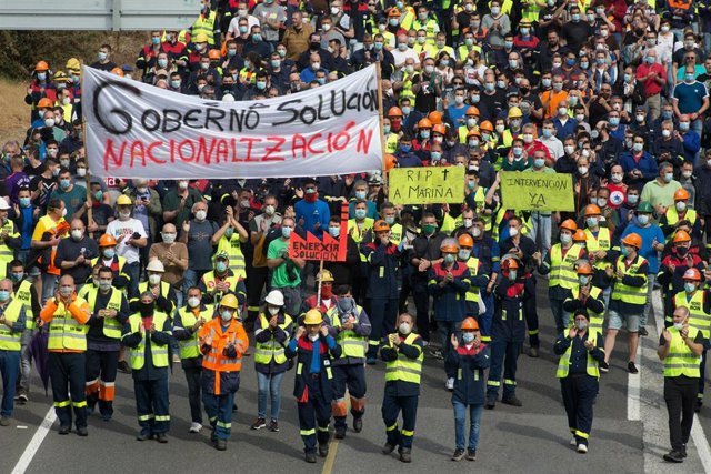 Participantes protegidos con mascarilla sujetan pancartas durante la manifestación del comité de empresa de Alcoa entre la factoría y la localidad de San Cibrao a 2 de junio de 2020.