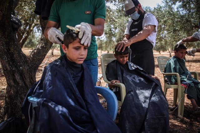 Peluqueros voluntarios cortan el pelo a un grupo de niños sirios en el campo de refugiados de Qah, en la frontera norte con Turquía.