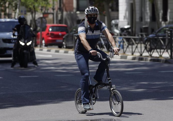 Un hombre protegido con mascarilla monta en una bicicleta 