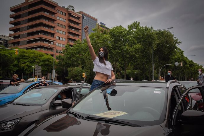 Una manifestante sentada en la ventana de un coche protesta contra el cierre de Nissan en una movilización que ha congregado a un millar de vehículos en la avenida Diagonal de Barcelona este jueves