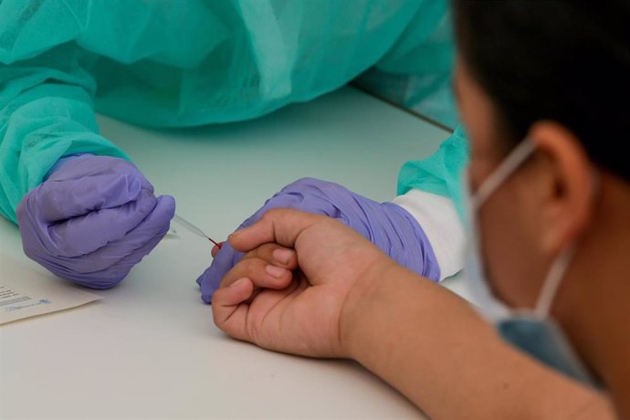 Una trabajadora sanitaria totalmente protegida, realiza una prueba diagnóstica del coronavirus