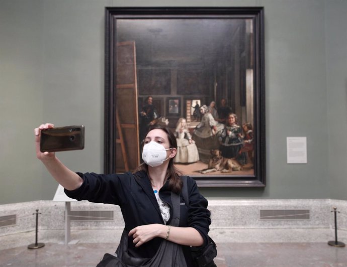 Una persona protegida con mascarilla se realiza una fotografía con una obra durante la presentación de la reapertura del Museo del Prado, que tendrá lugar el sábado 6 de junio después de su cierre, a mediados del mes de marzo, con motivo de la pandemia 