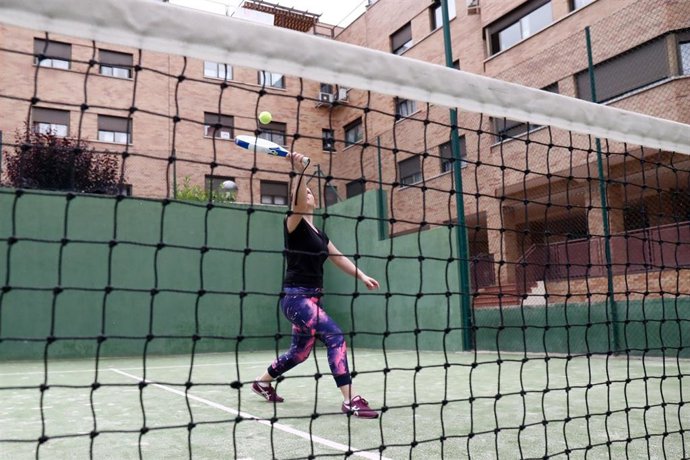 Una madre juega con su hijo preadolescente al pádel en una pista.