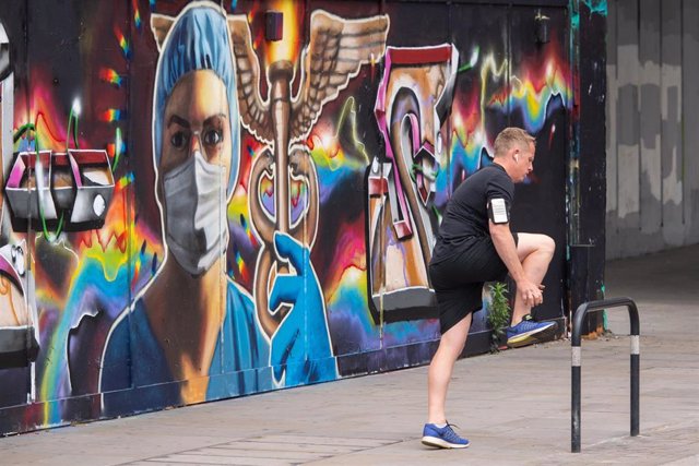 Un hombre junto a un mural de un trabajador sanitario en Londres