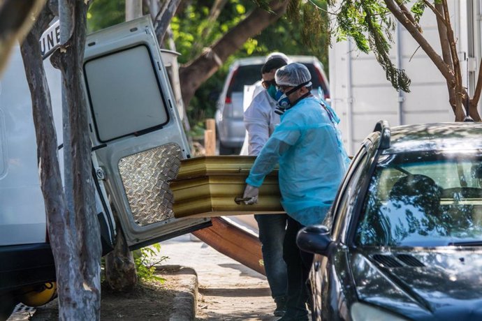 Dos personas transportan el ataúd de una víctima por la COVID-19 en Río de Janeiro, Brasil.