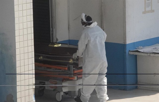 Un trabajador sanitario llevando un féretro dentro de una clínica en Río de Janeiro