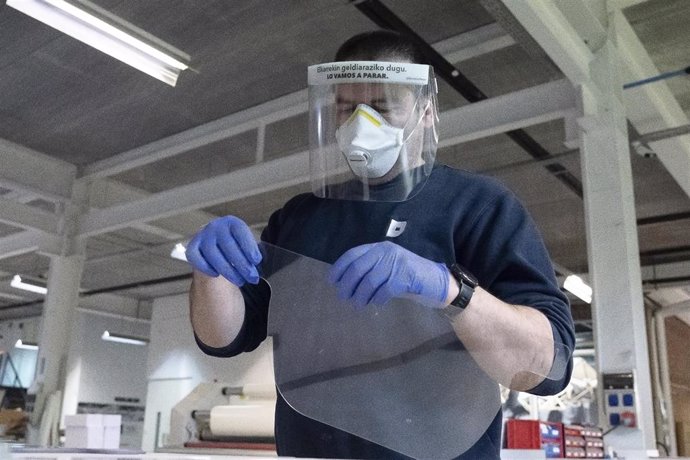 Un operario protegido con máscara prepara material en la empresa Estudios Durero, que se ha  reconvertido para fabricar miles de batas para el personal sanitario 