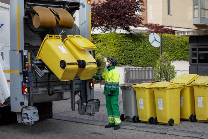 Un operario de recogida de residuos protegido con mascarilla observa cómo se tritura el contenido de cubos de basura amarillos destinados a envases en un camión de limpieza en una calle de la capital durante el día 33 del estado de alarma, en Madrid (Es