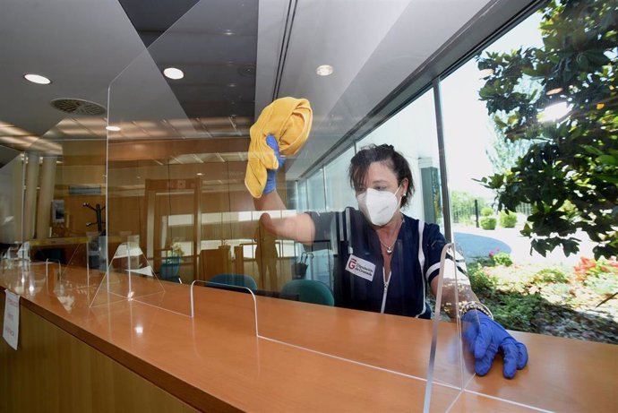 Trabajadora de la Diputación limpiando una mampara en un punto de atención al público
