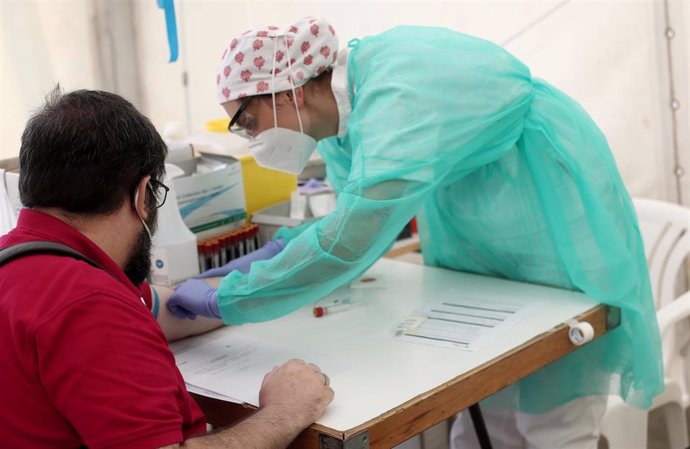 Un sanitario junto a un paciente durante una jornada del test serológico masivo de coronavirus que el Ayuntamiento de la localidad madrileña de Torrejón desplegó para los vecinos.