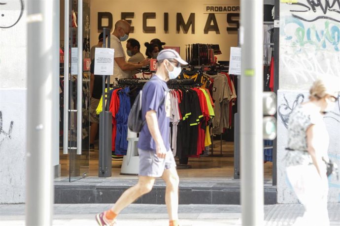 Un hombre protegido con mascarilla pasa junto a una tienda Décimas abierta durante la fase 1 de la desescalada en la que se permite reapertura de locales y establecimientos minoristas con una superficie igual o inferior a 400 metros cuadrados.