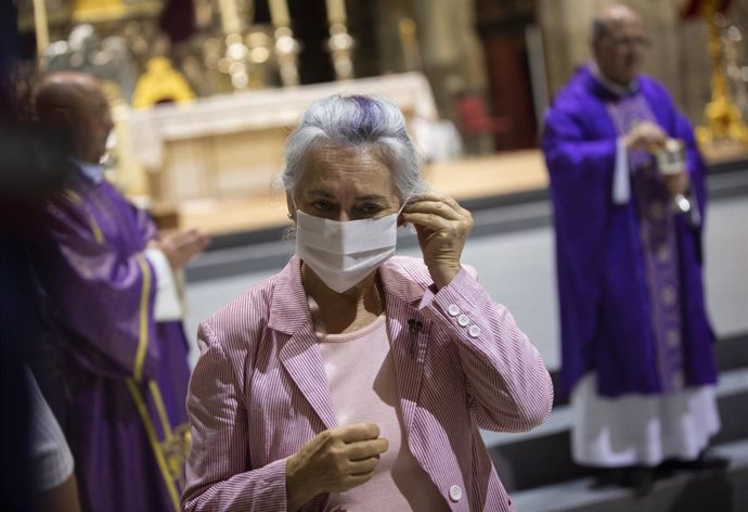Una mujer se coloca la mascarilla tras comulgar en el funeral en recuerdo y homenaje a las víctimas del coronavirus. En la Catedral.(Sevilla, Andalucía, España), a 04 de junio de 2020.