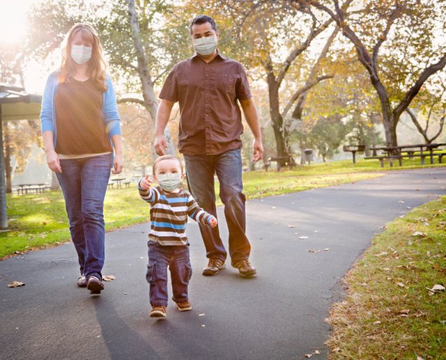 Familia con mascarilla en el parque.