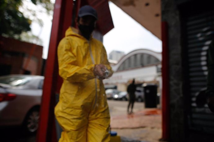 Un trabajador desinfectando la entrada a un mercado por el coronavirus. 