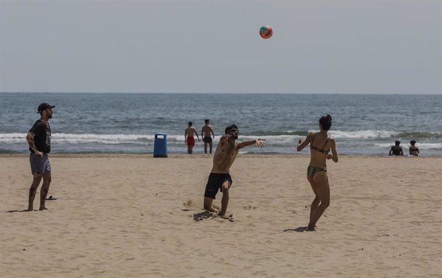 Varias personas juegan con una pelota en la Playa de la Malvarrosa de València