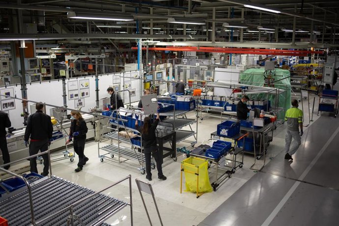 Operarios trabajan en la cadena de producción y montaje de una empresa de automoción