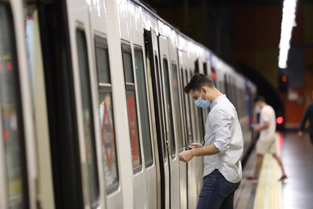 Un pasajero abre la puerta de un tren de Metro de Madrid.