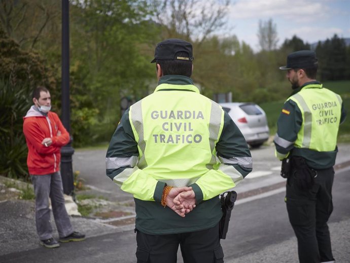 Dos agentes de la Guardia Civil de Tráfico hablan con un hombre en un control policial durante el día 32 del estado de alarma, 15 de abril.