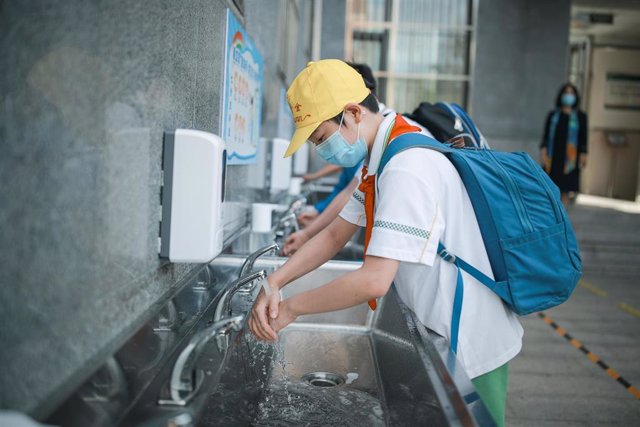 Estudiantes de una escuela de Pekín se lavan y desinfectan las manos antes de entrar a clase.