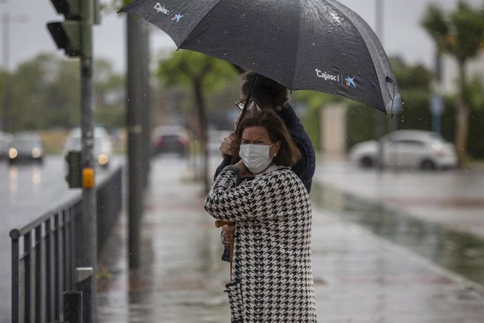 Dos personas bajo un paraguas durante una tormenta durante el Estado de Alarma, en Sevilla