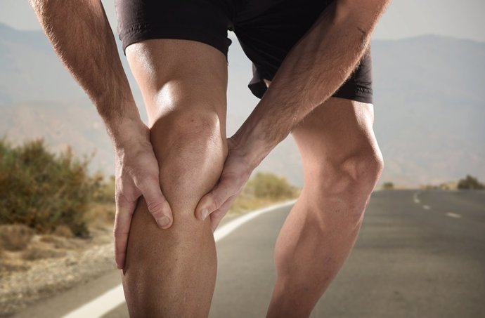 Joven deportista sosteniendo la rodilla, dolor por lesión muscular.