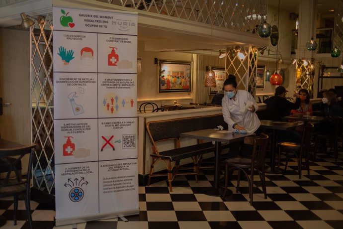 Una cambrera neteja una taula de l'histric local barceloní Núria, que ha simbolitzat aquest dilluns al matí, amb un esmorzar popular, la reobertura de bars i restaurants de la Rambla per l'inici de la Fase 2 de la desescalada pel coronavirus.  