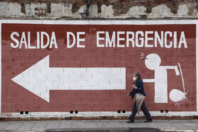 Una mujer camina delante de un mural  en Málaga, donde va protegida por una mascarilla por el virus COVID-19.-Málaga a 14 de mayo del 2020