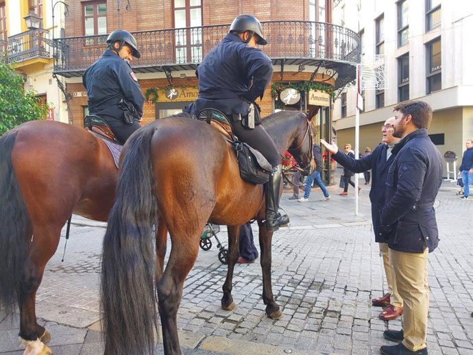 El concejal del PP Jesús Gómez y el portavoz de esta formación en el Ayuntamiento de Sevilla, Beltrán Pérez, junto a dos agentes de la Policía Nacional, en una imagen de archivo.