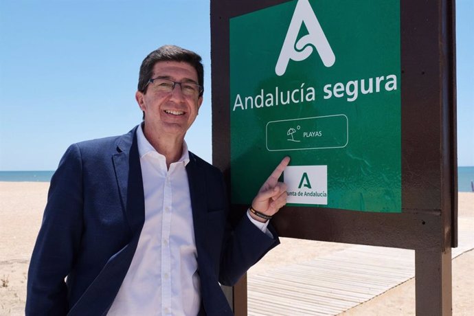 El vicepresidente de la Junta de Andalucía y consejero de Turismo, Regeneración, Justicia y Administración Local, Juan Marín, junto al distintivo 'Andalucía Segura' en la playa de La Antilla (Huelva).