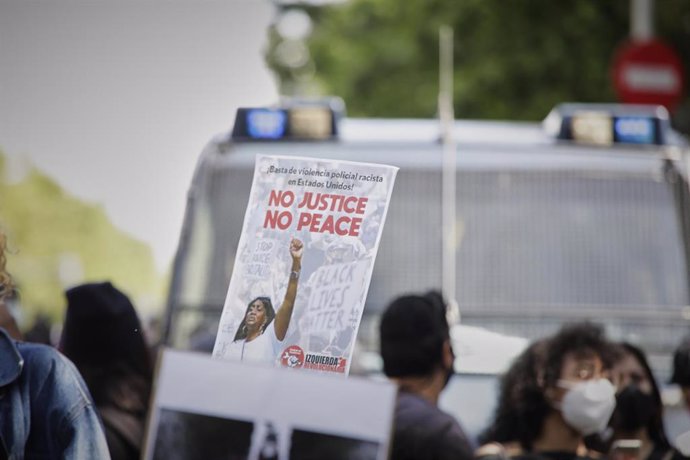 Participante alza un cartel que dice '¡Basta de violencia policial racista en Estados Unidos! No justice, no peace' 