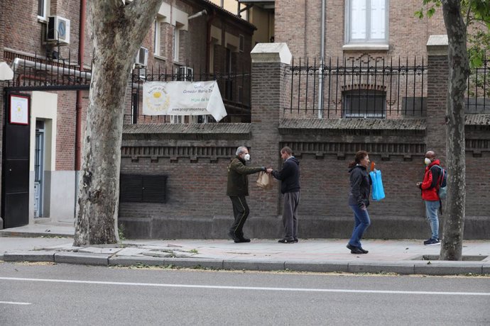 Varias personas esperan en cola para entrar en el comedor de las Hijas de la Caridad de San Vicente de Paúl en el madrileño barrio de Chamberí, donde se reparten alimentos a los más necesitados, en Madrid (España) a 28 de abril de 2020.