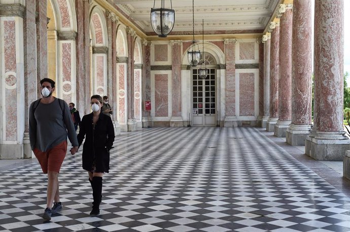 Dos personas con mascarilla en el Palacio de Versalles de Francia