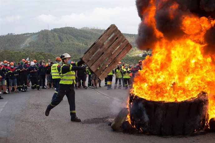 Un participante echa un palé de madera a la barricada realizada a las puertas de la factoría de San Cibrao, donde participantes han quemado de neumáticos, en una nueva manifestación del comité de empresa de Alcoa.